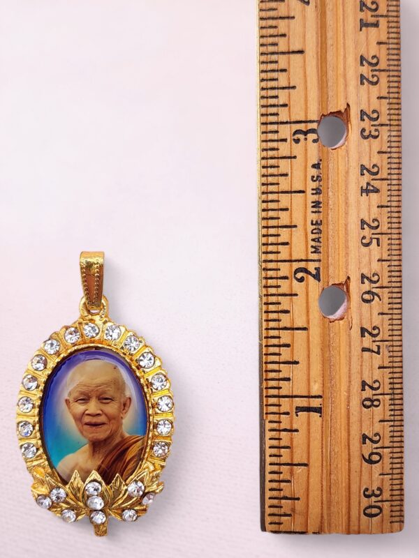 Double-sided Thai Buddhist amulet pendant with Ajahn Maha Bua on the front and Mahabodhi Temple on the back, framed in gold with crystal accents.