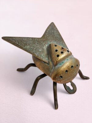Vintage brass fly-shaped incense holder with etched detailing and patina, handmade in India and wall-mountable.